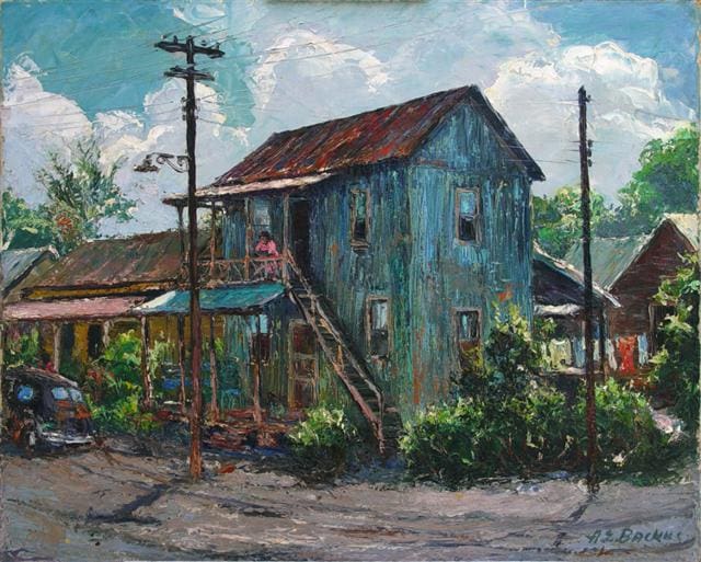 A rustic, two-story wooden house with a tin roof and an external staircase. There's a person sitting on the balcony and greenery surrounding the house. Power lines are visible, and a vintage car is parked nearby.