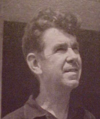 A man with curly hair is looking to the upper side, shown in a black-and-white image.